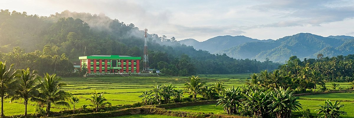 Rice terraces and the Municipal Hall of Guipos below a forested mountain ridge